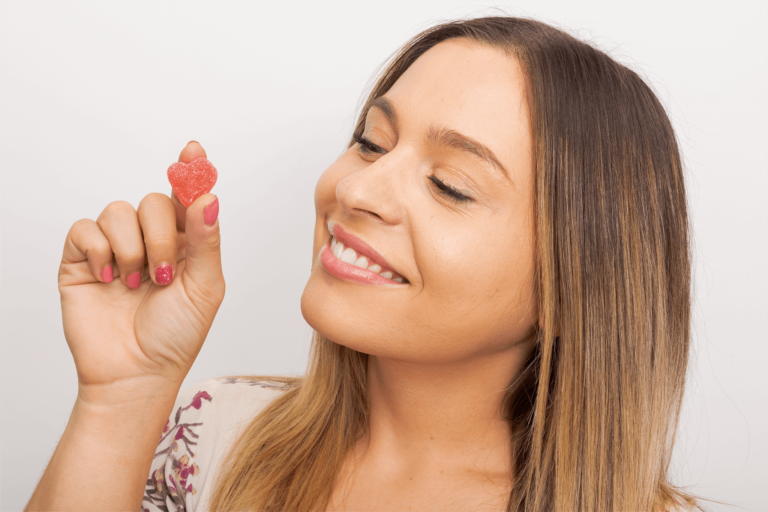 Woman Smiling While Holding a CBD Gummy | Veritas Farms